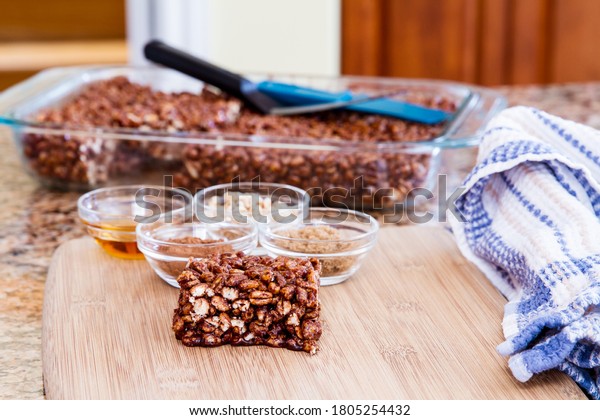 Large\
puffed wheat square treat with small glass bowls of raw ingredients\
beside; delicious and chewy puffed wheat\
squares