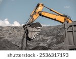 Large quarry dump excavator. Big yellow mining excavator at work site. Loading coal into body truck. Mining digger, mining machinery to loading rock. Production useful minerals. Digger loading coal