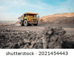 Large quarry dump truck. Big yellow mining truck at work site. Loading coal into body truck. Production useful minerals. Mining truck mining machinery to transport coal from open-pit production