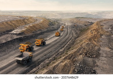 Large quarry dump truck. Big yellow mining truck at work site. Loading coal into body truck. Production useful minerals. Mining truck mining machinery to transport coal from open-pit production - Shutterstock ID 2037648629
