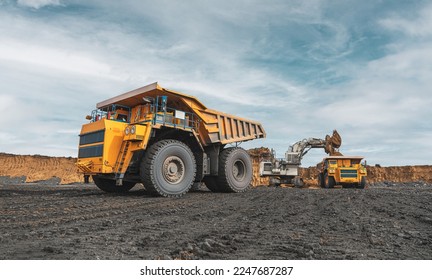 Large quarry dump truck. Big yellow mining truck at work site. Loading coal into body truck. Production useful minerals. Mining truck mining machinery to transport coal from open-pit production - Shutterstock ID 2247687287