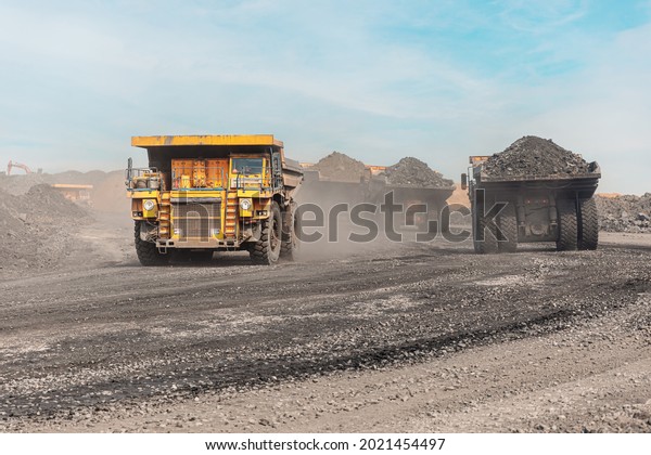 Large quarry dump truck. Big yellow mining
truck at work site. Loading coal into body truck. Production useful
minerals. Mining truck mining machinery to transport coal from
open-pit production