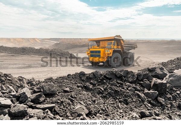 Large quarry dump truck. Big yellow mining
truck at work site. Loading coal into body truck. Production useful
minerals. Mining truck mining machinery to transport coal from
open-pit production