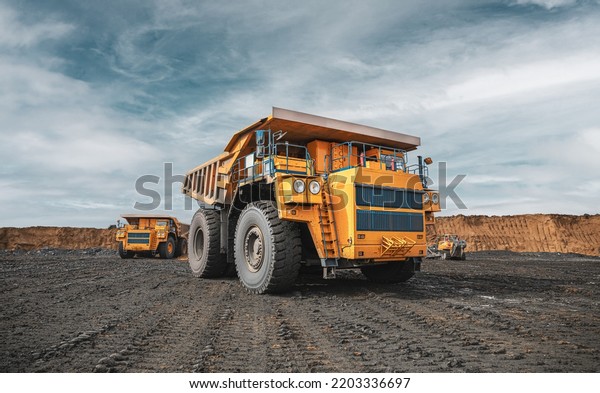 Large quarry dump truck. Big yellow mining\
truck at work site. Loading coal into body truck. Production useful\
minerals. Mining truck mining machinery to transport coal from\
open-pit production