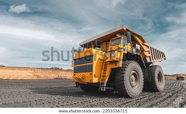 Large quarry dump truck. Big yellow mining\
truck at work site. Loading coal into body truck. Production useful\
minerals. Mining truck mining machinery to transport coal from\
open-pit production
