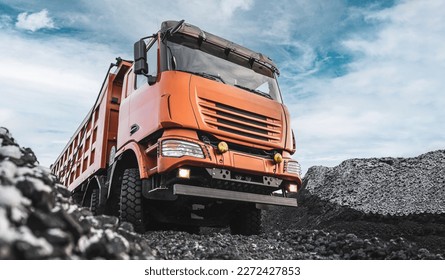 Large quarry dump truck. Dump truck carrying coal, sand and rock. Trucks moving on dirt country road in forest. Mining truck mining machinery to transport coal from open-pit. Transportation of mineral