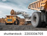 Large quarry dump truck and excavator. Big mining truck work coal deposit. Loading coal into body truck. Production useful minerals. Mining mining machinery to transport coal from open-pit production