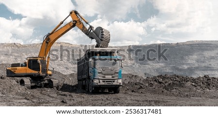Large quarry dump truck and excavator. Big mining truck work coal deposit. Loading coal into body truck. Production useful minerals. Mining mining machinery to transport coal from open-pit production.