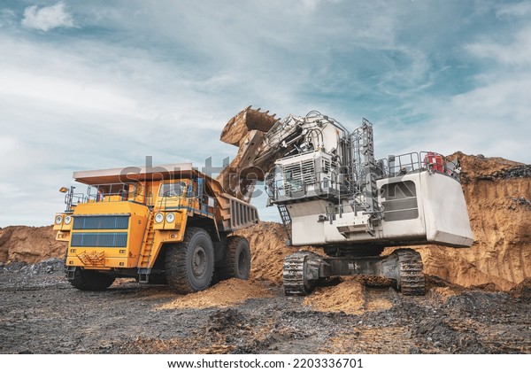 Large quarry dump truck and excavator. Big\
mining truck work coal deposit. Loading coal into body truck.\
Production useful minerals. Mining mining machinery to transport\
coal from open-pit\
production