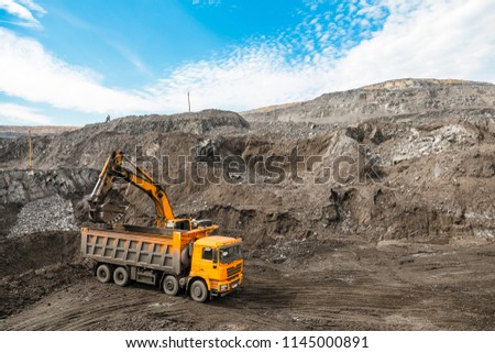 Large quarry dump truck. Loading the rock in dumper. Loading coal into body truck. Production useful minerals. Mining truck mining machinery, to transport coal from open-pit as the coal production.