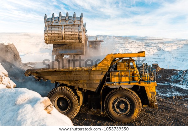 Large quarry dump truck. Loading the rock in\
dumper. Loading coal into body truck. Production useful minerals.\
Mining truck mining machinery, to transport coal from open-pit as\
the Coal Production.
