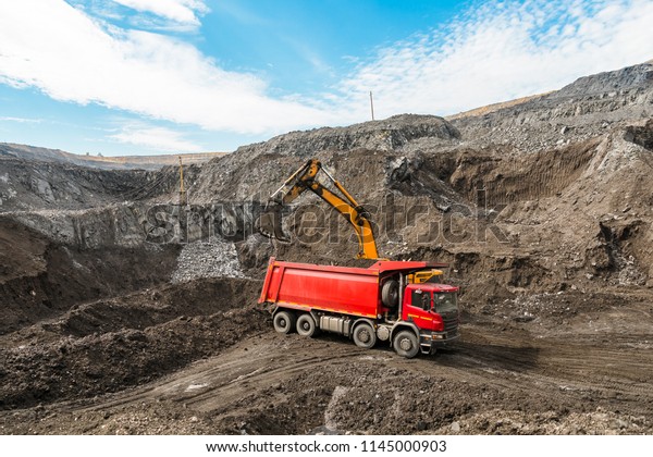 Large quarry dump truck. Loading the rock in\
dumper. Loading coal into body truck. Production useful minerals.\
Mining truck mining machinery, to transport coal from open-pit as\
the coal production.