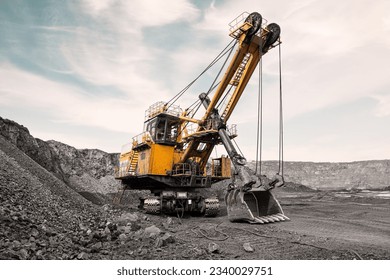 Large quarry excavator. Big yellow mining digger at work site. Loading coal into body truck. Production useful minerals. Mining backhoe mining machinery to transport coal from open-pit production - Powered by Shutterstock