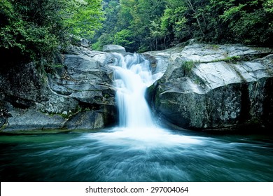 Large Rain Forest Waterfall, Sun Beams, And Mossy Rocks