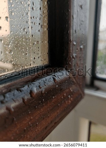 Large raindrops on a window frame during a downpour