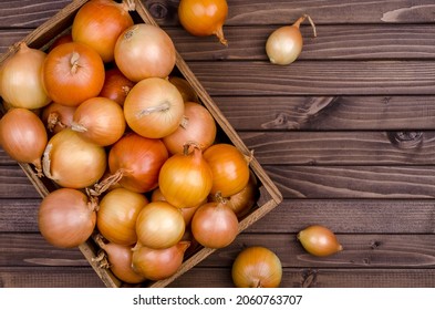 Large raw onions in a box on a wooden background. Design concept. View from above.