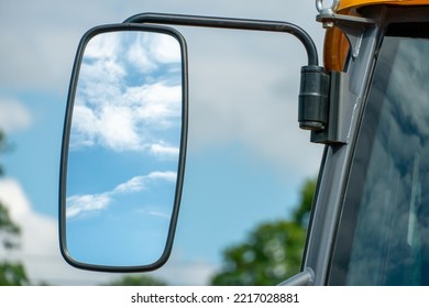Large rear view mirror on the truck cab. A car for the transportation of goods and goods. transport logistics company. View of the rear view mirror of the truck against the background of clouds.