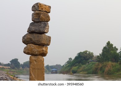 Large rectangular stones placed stacked on towering concrete pillars in the river villages.