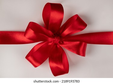 A Large Red Bow Made Of Red Ribbon On A White Gift Box