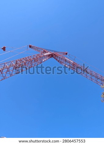 a large red construction crane boom against a clear blue sky
