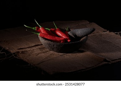 Large red and green chilies are ready to be ground in a stone mortar and pestle, mixed with shallots and garlic to make a spicy chili sauce which is characterized by the presence of thin smoke. - Powered by Shutterstock