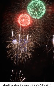Large red and green fireworks exploding together in the dark night sky.