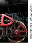 Large red iron wheel and mechanism of an old steam locomotive.