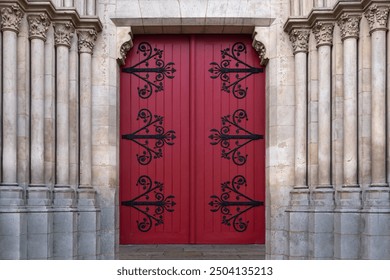 A large red wooden door with wrought iron curtains. They close the entrance to the room in the Gothic style - Powered by Shutterstock