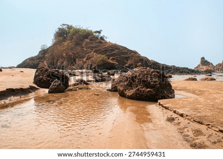 Large Reddish Rock Formations Resting on Sandy Shore At Nivati Beach in Maharashtra, India