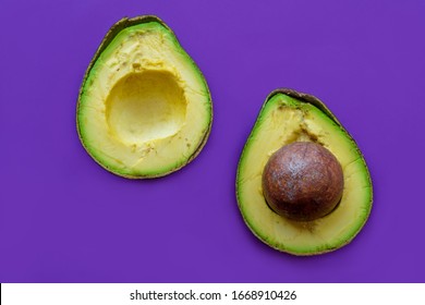 A Large And Ripe Avacado Is Cut In Half. Magenta Background.