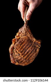 A Large Roasted Piece Of Mutton Steak, Pork, Veal Or Beef On Bones Cooked On An Air Fryer, In The Hands Of The Chef's Chief, A Background Image On A Black Background.