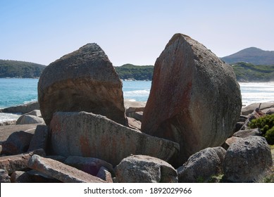 Large rock split in two with sea in background.