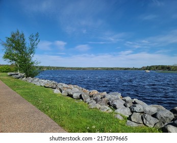 A Large Rock Wall Extending Along A Path Next To A River.