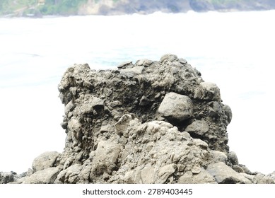 a large rock with waves in the background on the beach