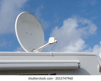 A large roof top satellite dish on top of a motorhome recreational vehicle against a blue sunny sky