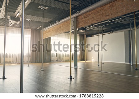 Large room with vertical poles for dancing, big mirror wall and window with curtains