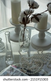 A Large Round Glass Table Stands By The Window With A Vase