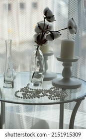A Large Round Glass Table Stands By The Window With A Vase