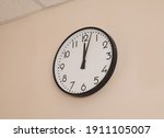 A large round indoor clock on the wall shows 12 o