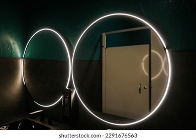 Large round mirror with lights in a downtown bar restroom 