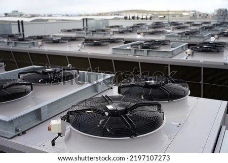 Large row of industrial condensers with fans on roof used in air conditioning, refrigeration, heat pump systems, green energy future concept