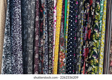 Large rows of pieces of fabric made of cotton, polyester, and other materials in different colors and prints of clothing, soft focus - Shutterstock ID 2262336209