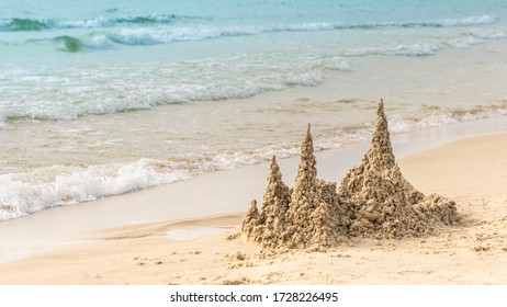 Large Sandcastle On Sandy Beach Near Waving Turquoise Sea. Sand House With Towers On Seaside Playing With Sand And Building Sandcastle On Seashore.