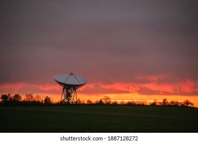 large satellite dish from the space station in the field on the horizon against the background of sunset