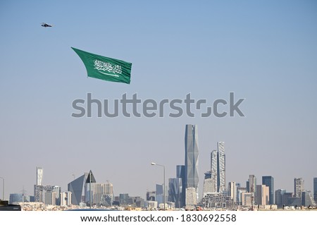 Large Saudi Arabia flag flies over Riyadh city with helicopter calibrating the National Day.