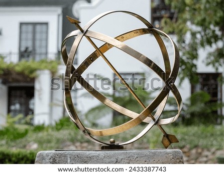 Large scale garden armillary sundial sphere with arrow and roman numerals. Hotel backyard