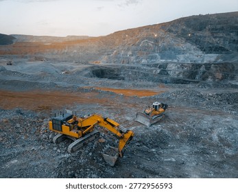 Large scale open pit mining operation with excavators and bulldozers at dusk, aerial view.