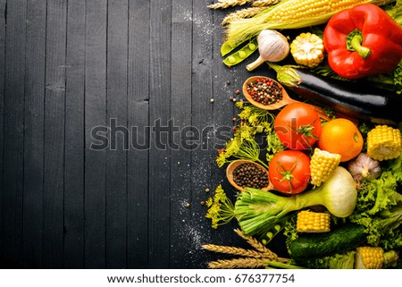 A large selection of raw fresh vegetables and spices. On a black wooden background. Top view. Free space for your text.