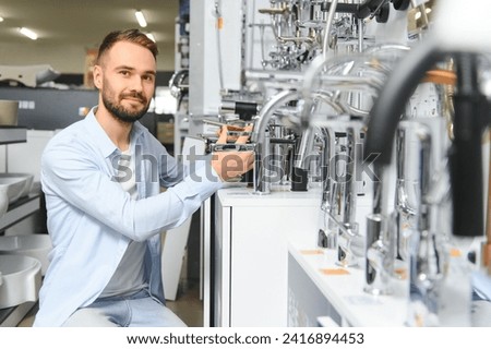 A large selection of water faucets. Man chooses a products in a sanitary ware store.