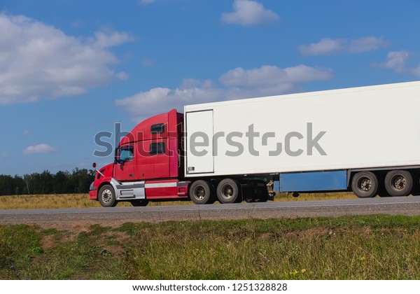 Large semi-trailer moves on a country road on a\
summer day.